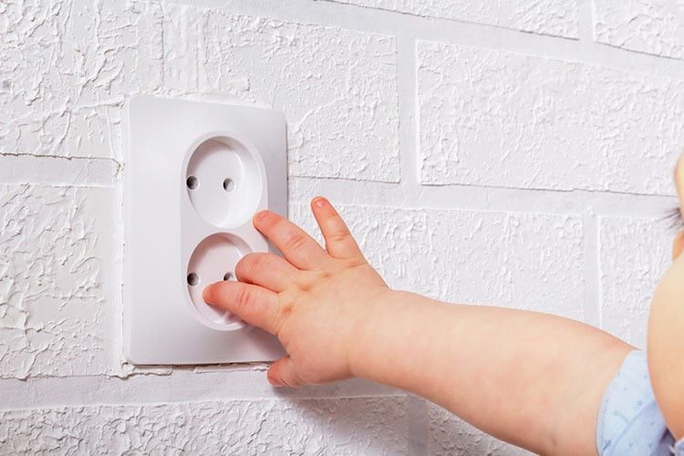 baby small hand near electrical socket. close up.